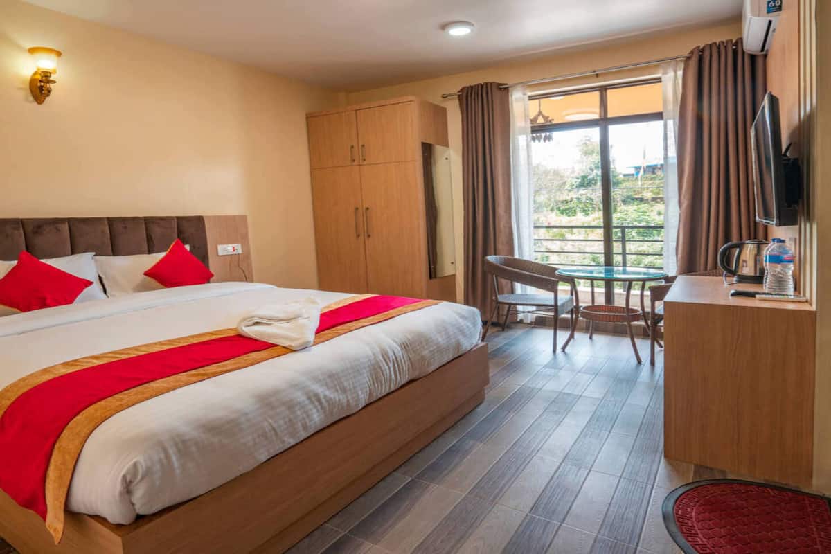 A hotel room with a large bed, a desk, and a chair.