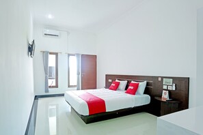Een hotelkamer met een bed, nachtkastje, spiegel en raam met gordijnen.