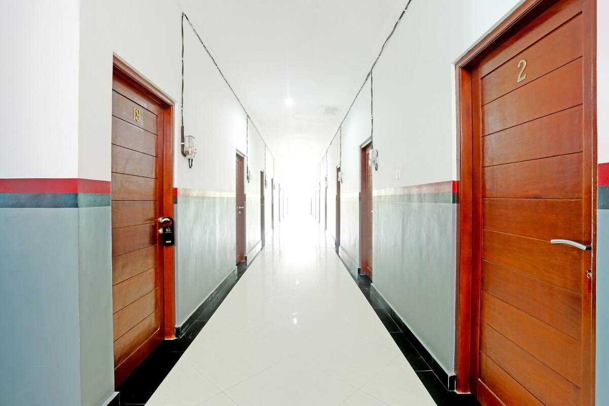 Un pasillo largo y estrecho con puertas de madera a ambos lados, numeradas 1 y 2, que conducen a habitaciones.