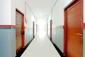 Een lange, smalle gang met houten deuren aan beide kanten, genummerd 1 en 2, die naar kamers leidt.