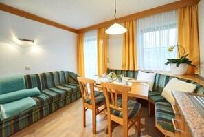 Une pièce chaleureuse avec un canapé, des fauteuils, une table à manger et une plante en pot.