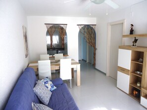 Relax and dine in this stylish living space, featuring a sofa, dining table, and kitchen area.