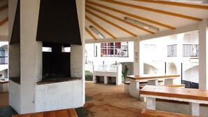 Relax by the central fireplace in this outdoor patio area, featuring a simple design with benches and a flat roof.