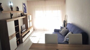 Een woonkamer met een blauwe bank, een televisie en een plafondventilator.