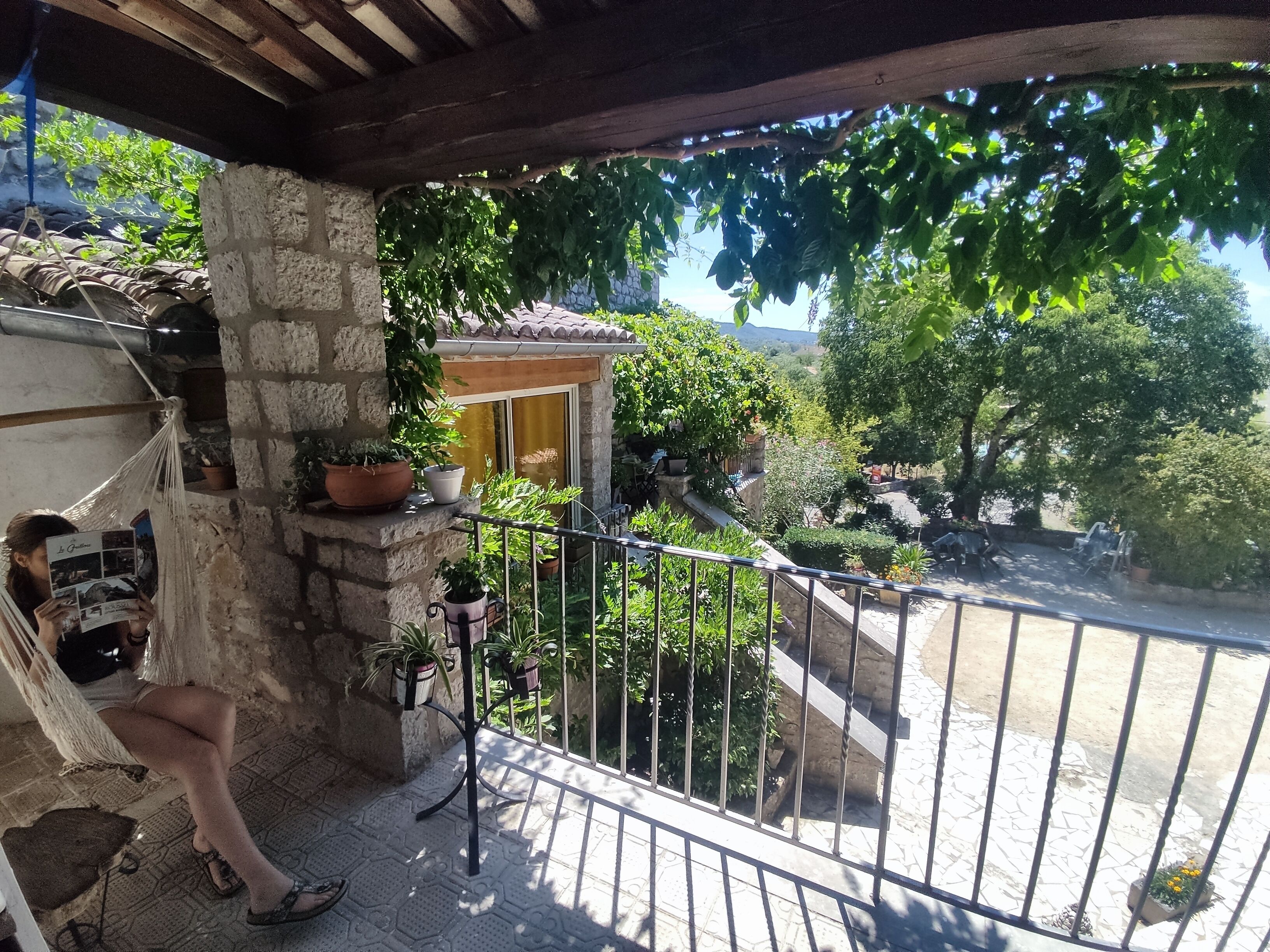 A balcony with a stone wall, potted plants, and a hammock.