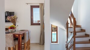 A dining area with a wooden table and chairs, a vase with flowers, and a television on the wall. - Sea views, short drive to the beach and shops! (Agios Nikolaos)