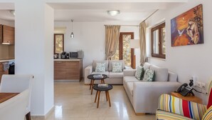 Una sala moderna con un sofá, una mesa de comedor y una cocina al fondo.