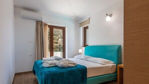 Un dormitorio con cama, ventana con cortinas, aire acondicionado y una mesita de noche.