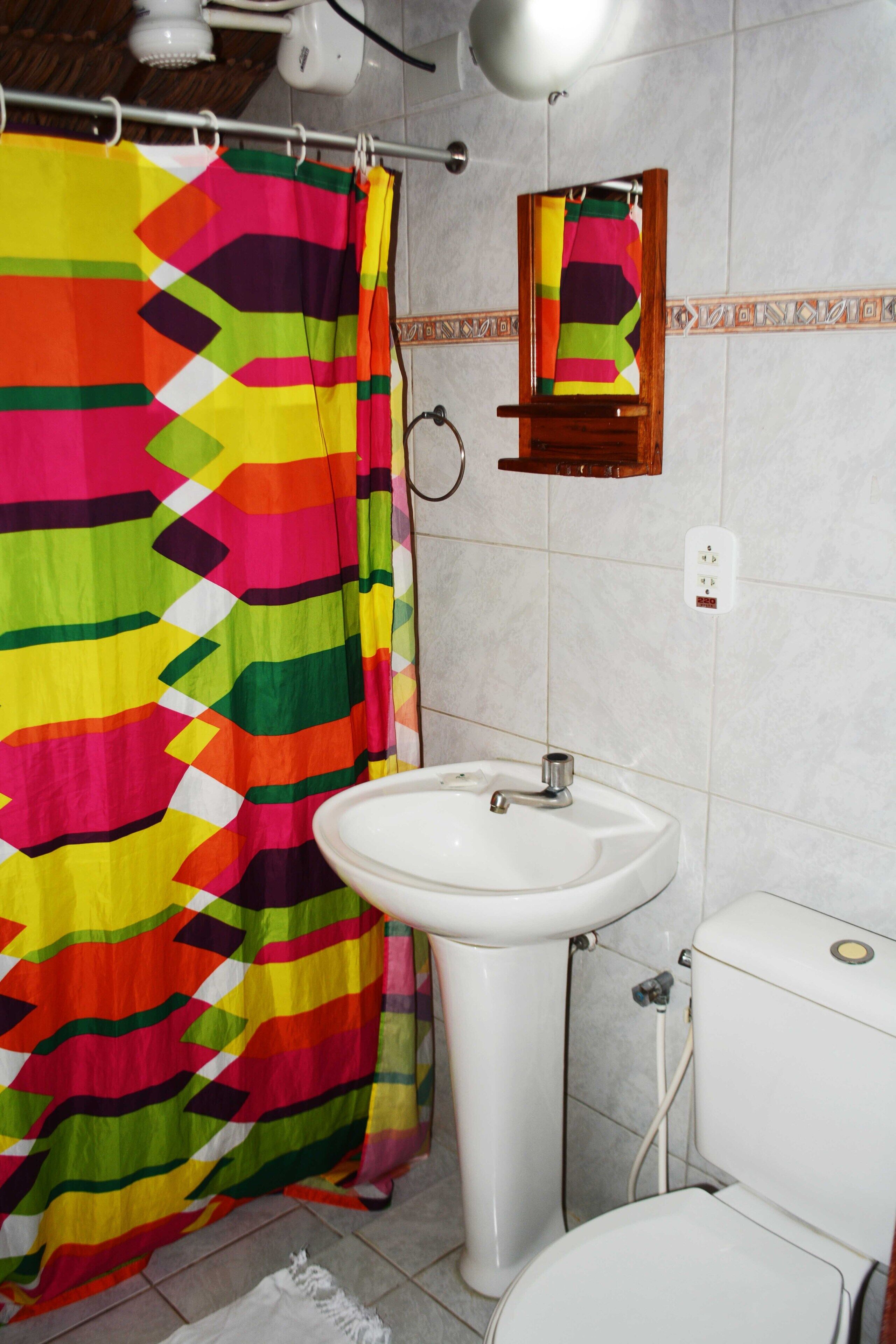 A bathroom with a colorful shower curtain, a white sink, and a toilet.
