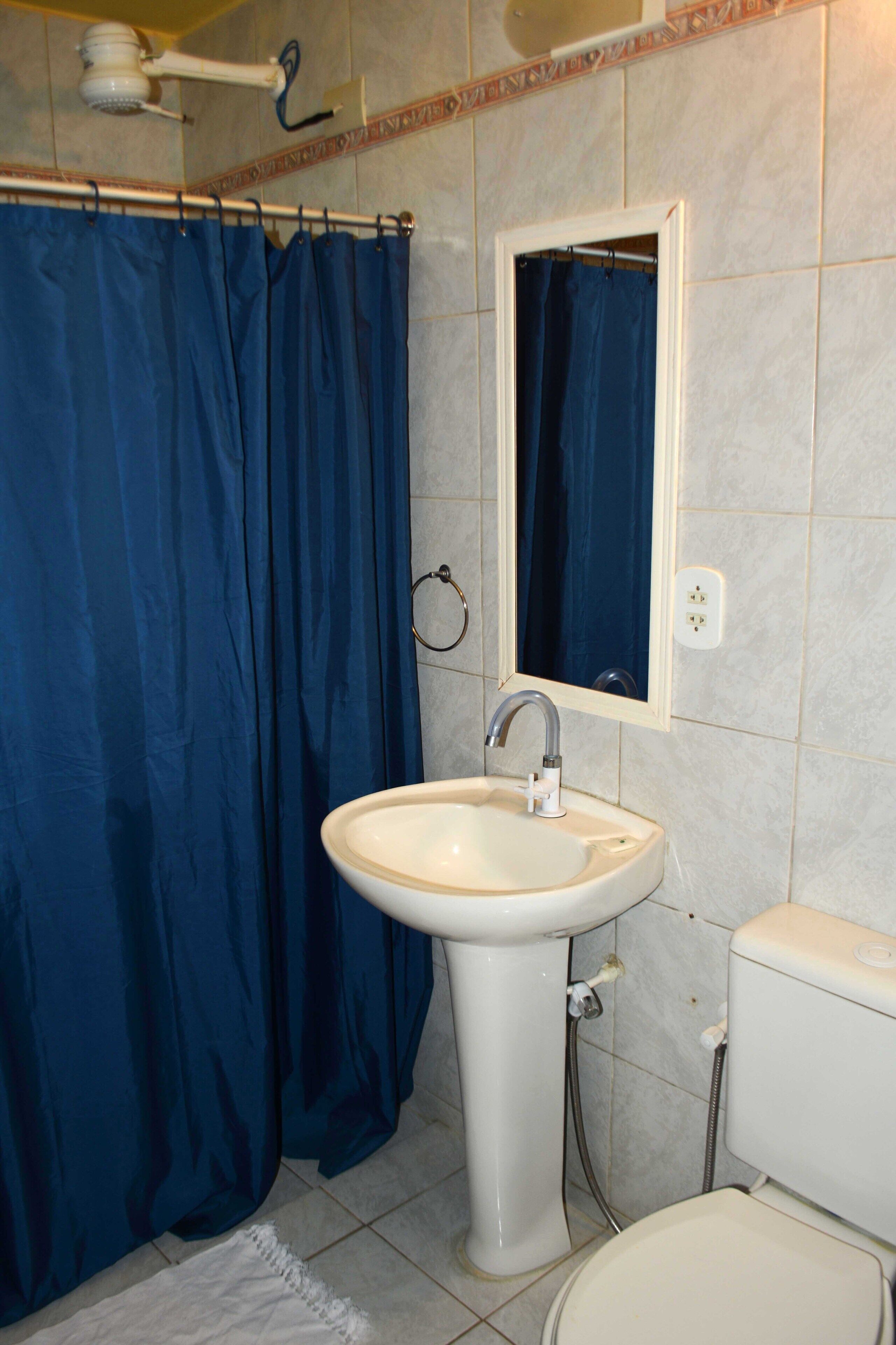 A bathroom with a white sink, a blue shower curtain, and a mirror above the sink.