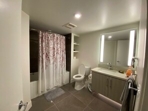 Bathroom features a shower area with a floral curtain, toilet, sink, and towel rack.