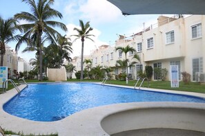 A swimming pool with palm trees and a building in the background.