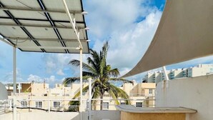 A rooftop terrace with a covered seating area, a palm tree, and a view of surrounding buildings. - Nice house in front of the beach, in Acapulco Diamante (Acapulco de Juárez)