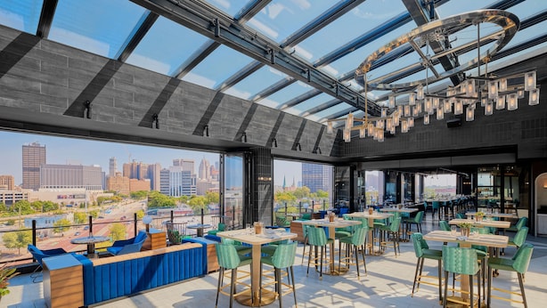 Un restaurant situé sur le toit d’un immeuble, offrant une vue sur la ville, doté d’un design moderne et disposant d’une terrasse.