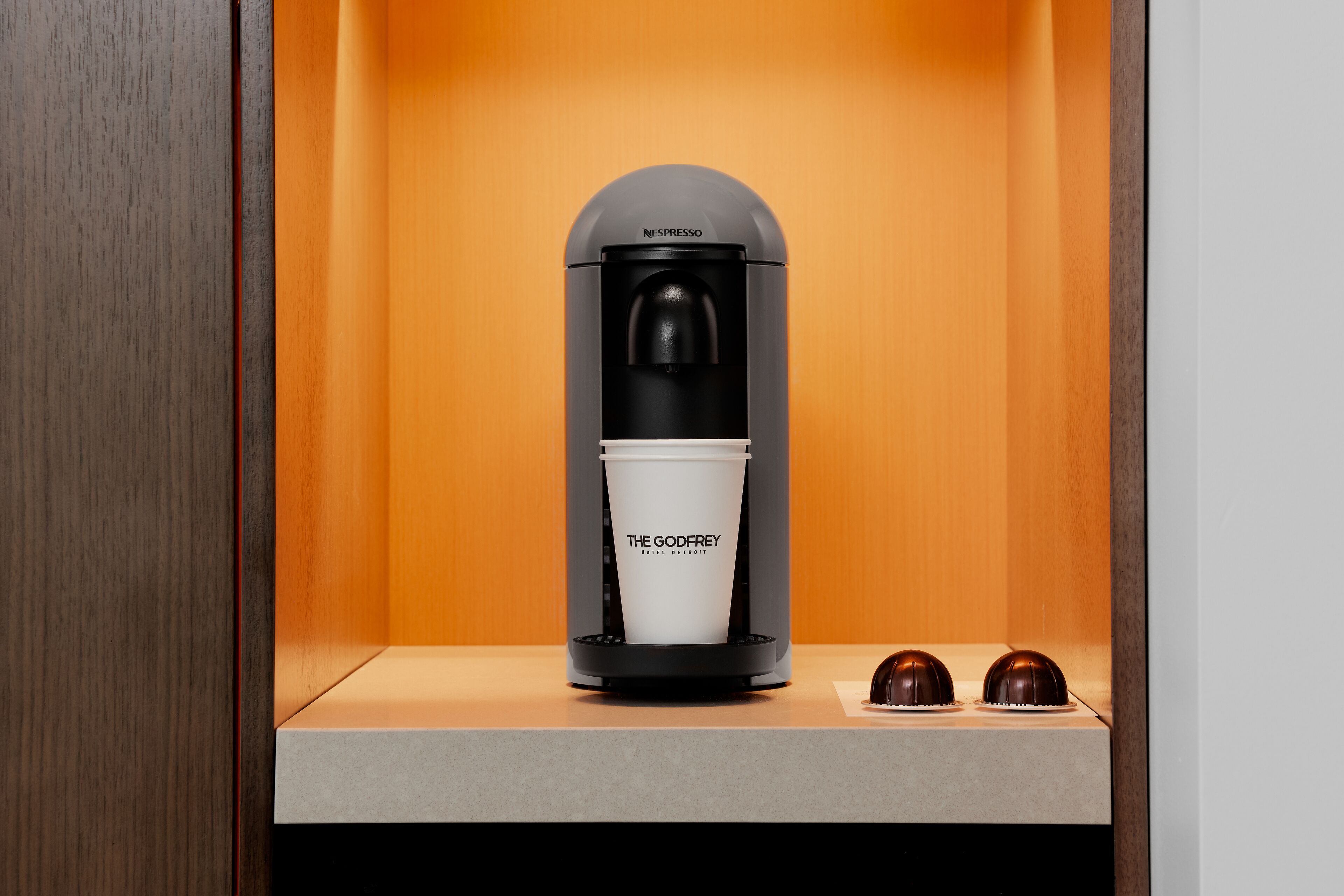 Una macchina Nespresso con una tazza con il marchio e due dessert al cioccolato su un bancone.