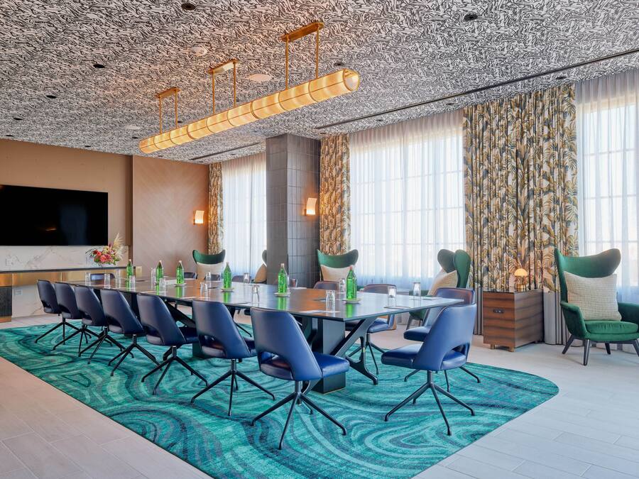 A conference room with a long table, blue chairs, and a patterned carpet.