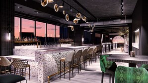 Un espace bar moderne doté d’un comptoir en marbre, de plusieurs tabourets et d’un éclairage suspendu.
