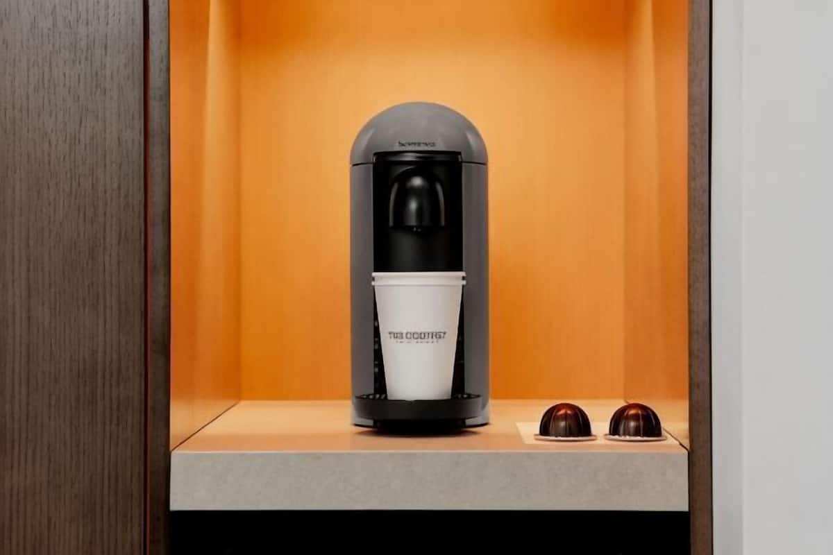 A coffee machine with a cup and two chocolate cups on a counter.