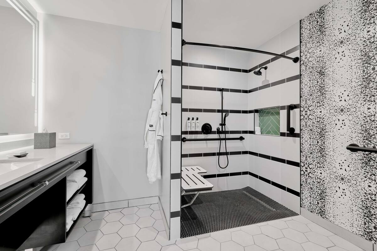 A modern bathroom with a shower, a vanity with a mirror, and a towel rack.