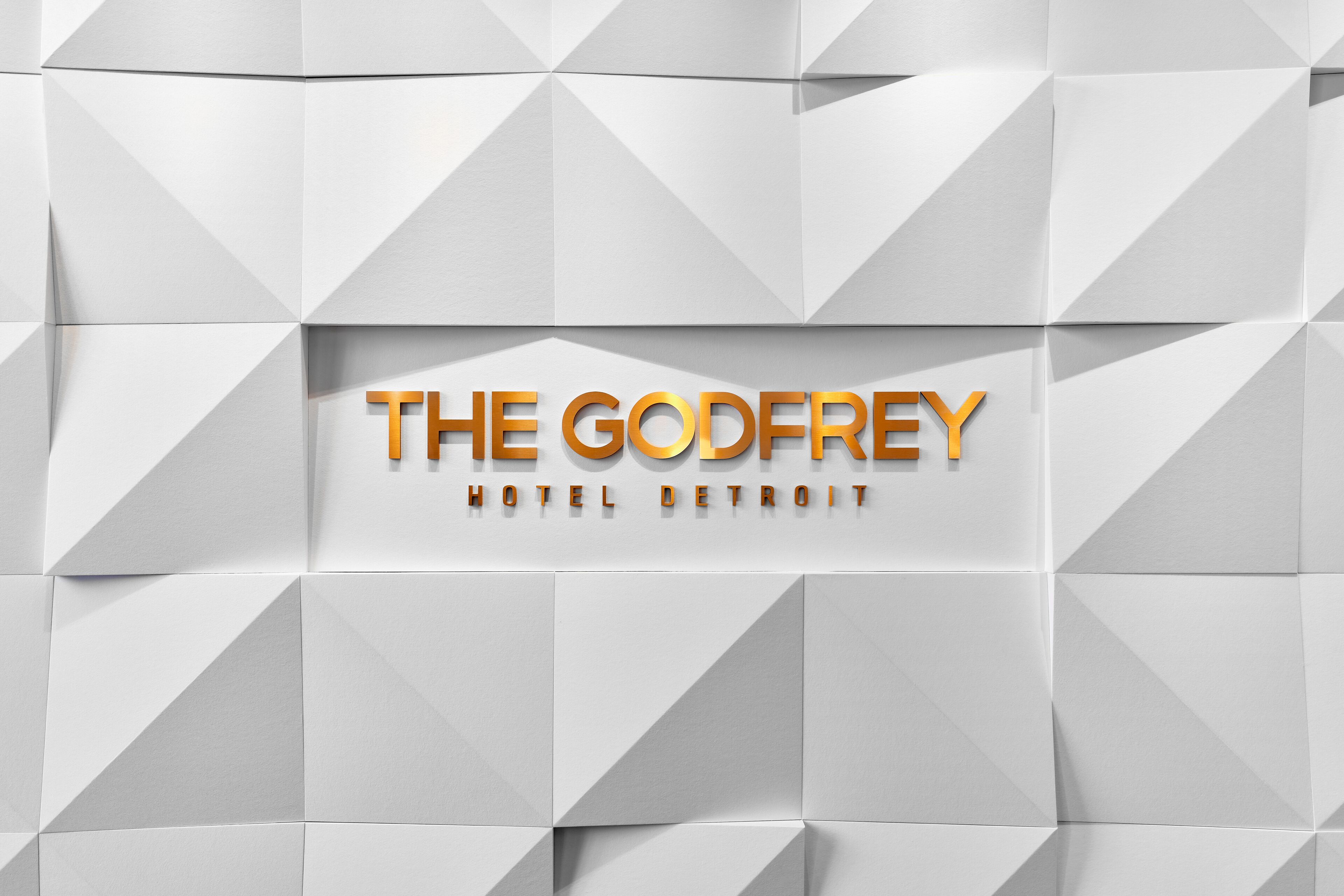 Un motif géométrique sur lequel figure en grand le texte « THE GODFREY HOTEL DETROIT ».