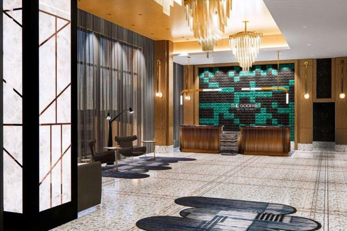 A modern lobby with a reception desk, seating area, and a decorative wall with a green pattern.