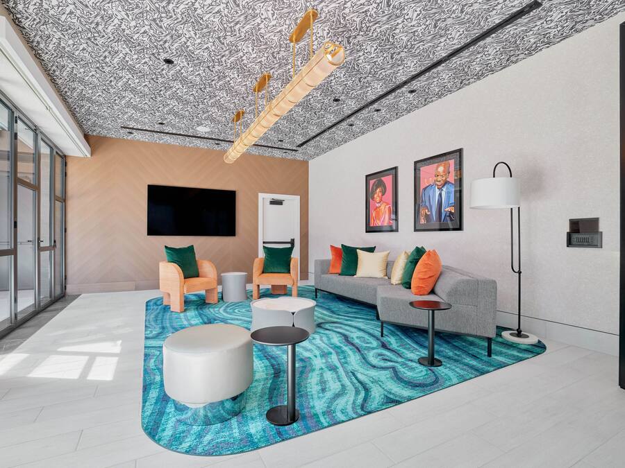 A modern living room with a patterned ceiling, a flat-screen TV, a sofa set, and a coffee table.