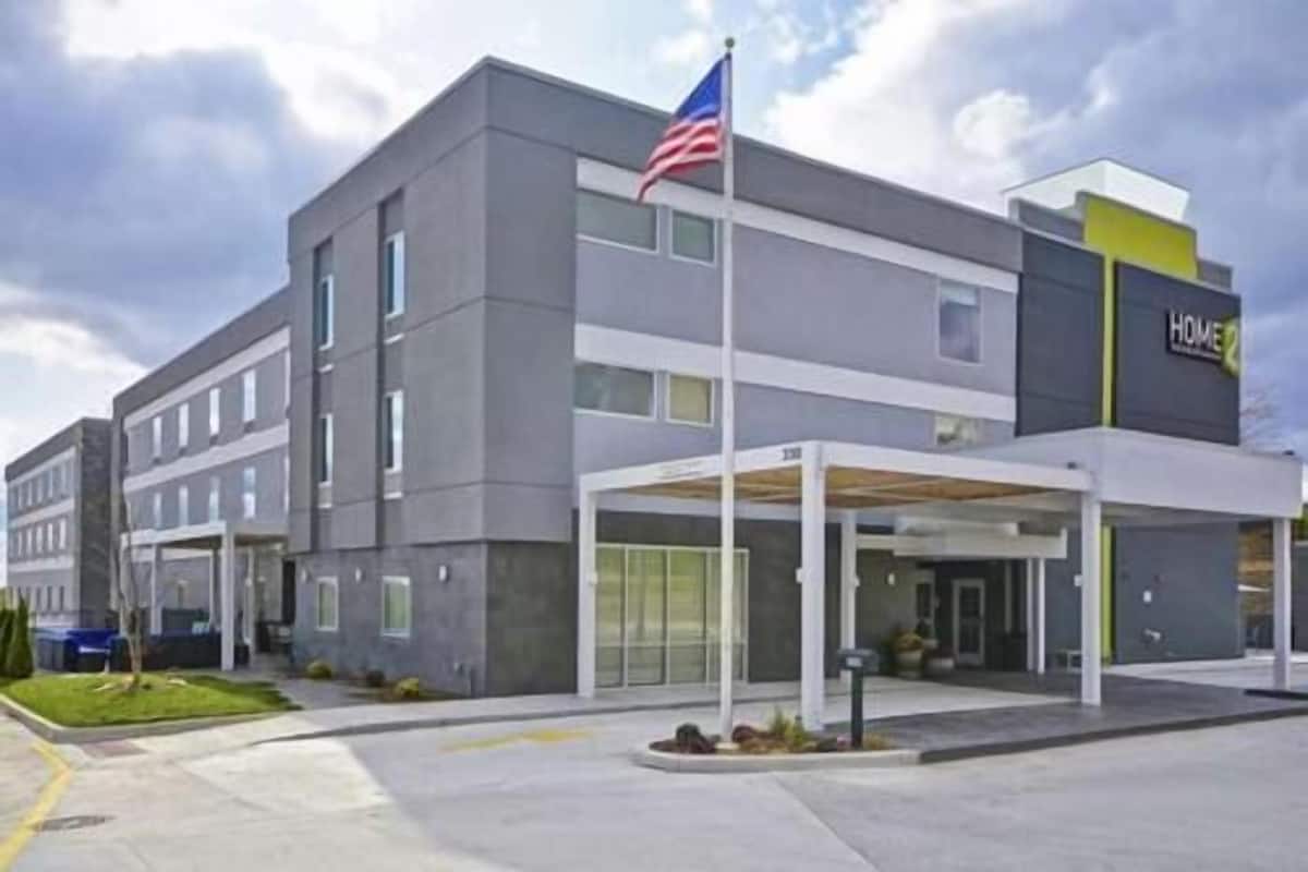 A modern hotel with a covered entrance, a flag, and a sign indicating it is a Home Inn.
