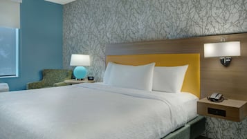 Een hotelkamer met een groot bed, een nachtkastje met een lamp, een telefoon en een wandlamp.