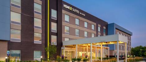A hotel with a modern design, featuring a covered entrance and a clear sign reading "HOME 2 SUITES BY HILTON".