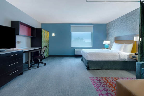 A hotel room with a bed, desk, chair, and a window with a view.