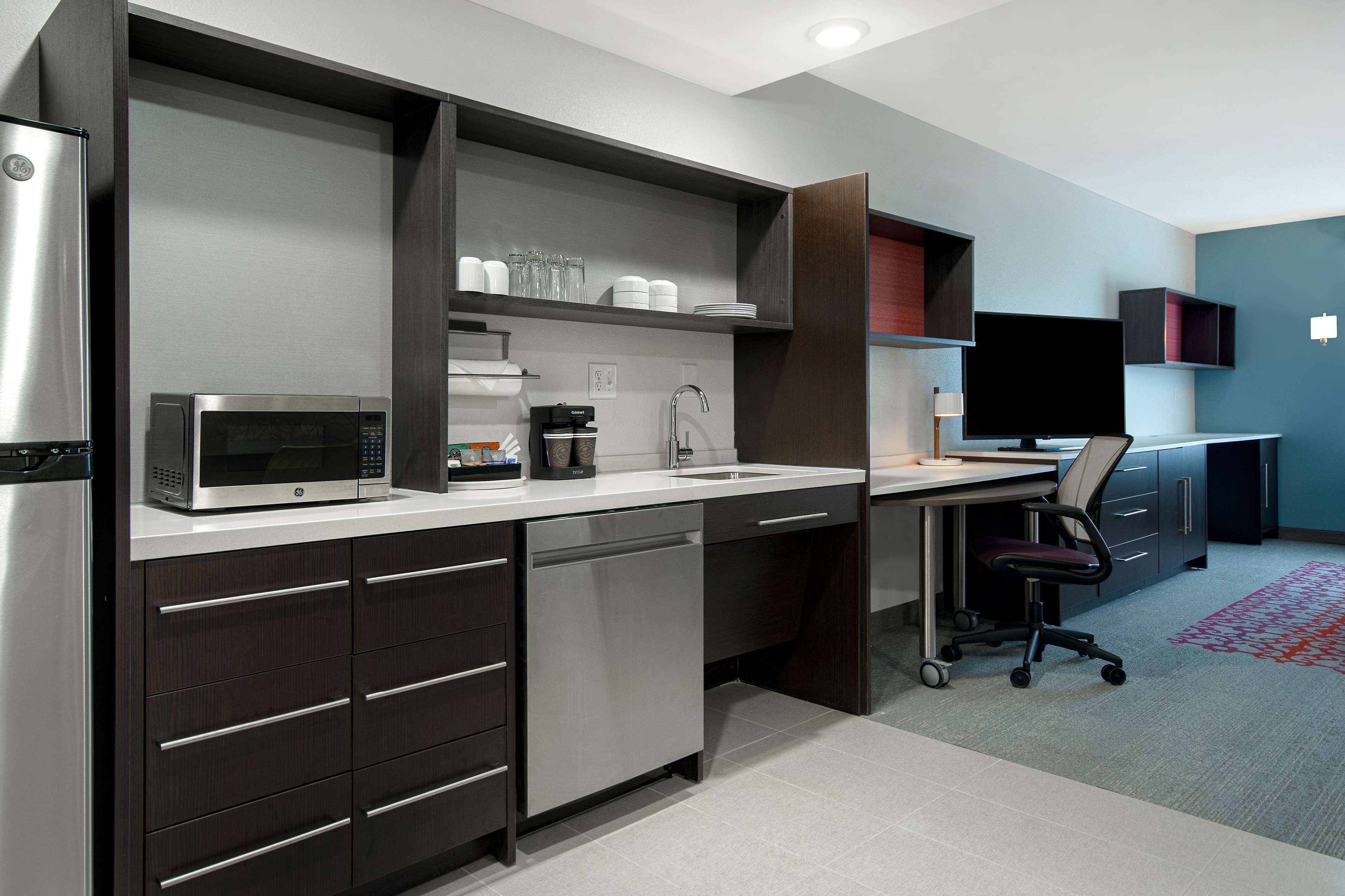 A modern kitchen with a built-in microwave, dishwasher, and a coffee maker.