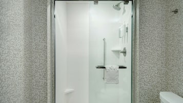 Ein modernes Badezimmer mit einer Duschkabine, weißen Fliesen und einer Toilette.