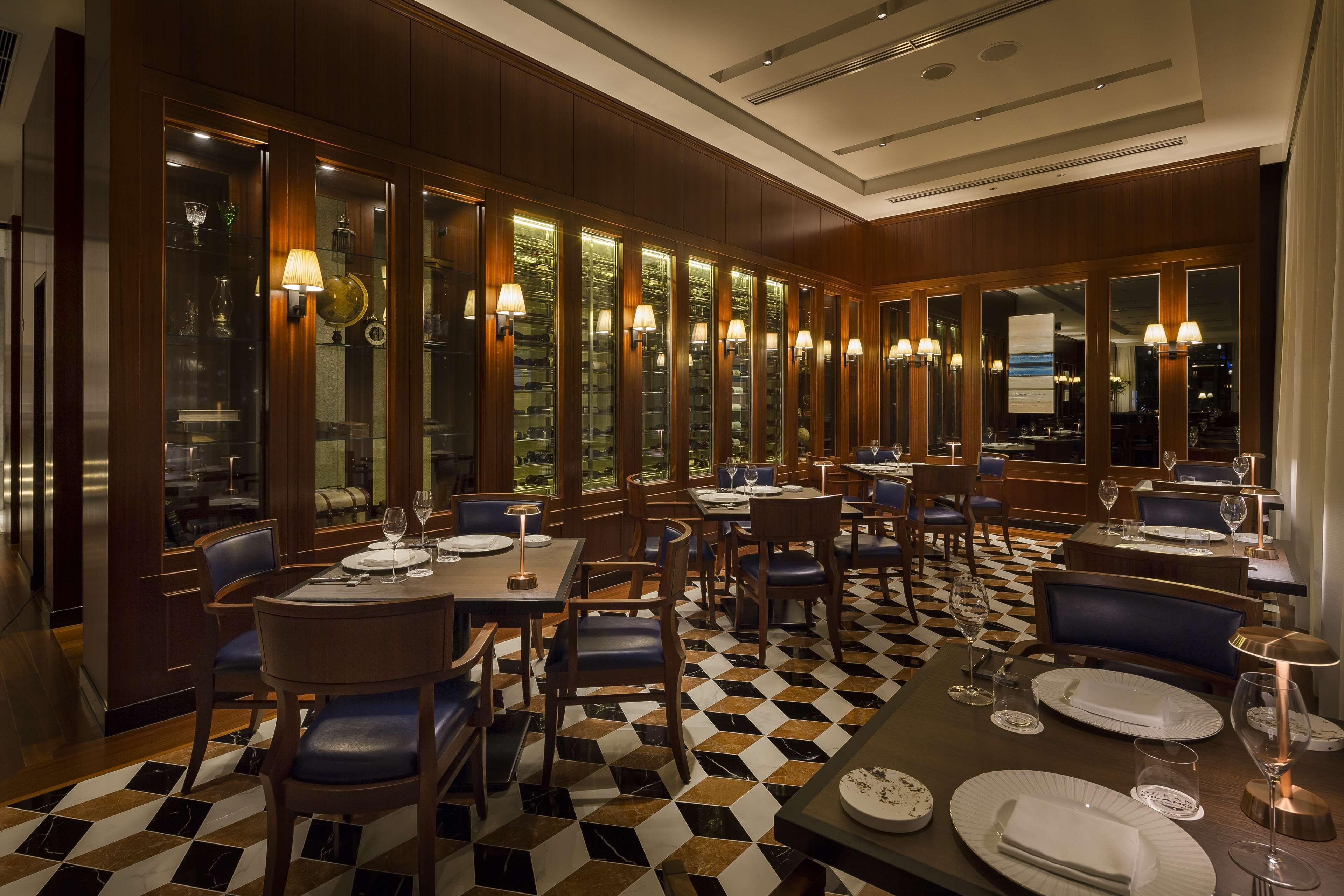 A restaurant with a checkered floor, wooden paneling, and multiple tables with chairs.