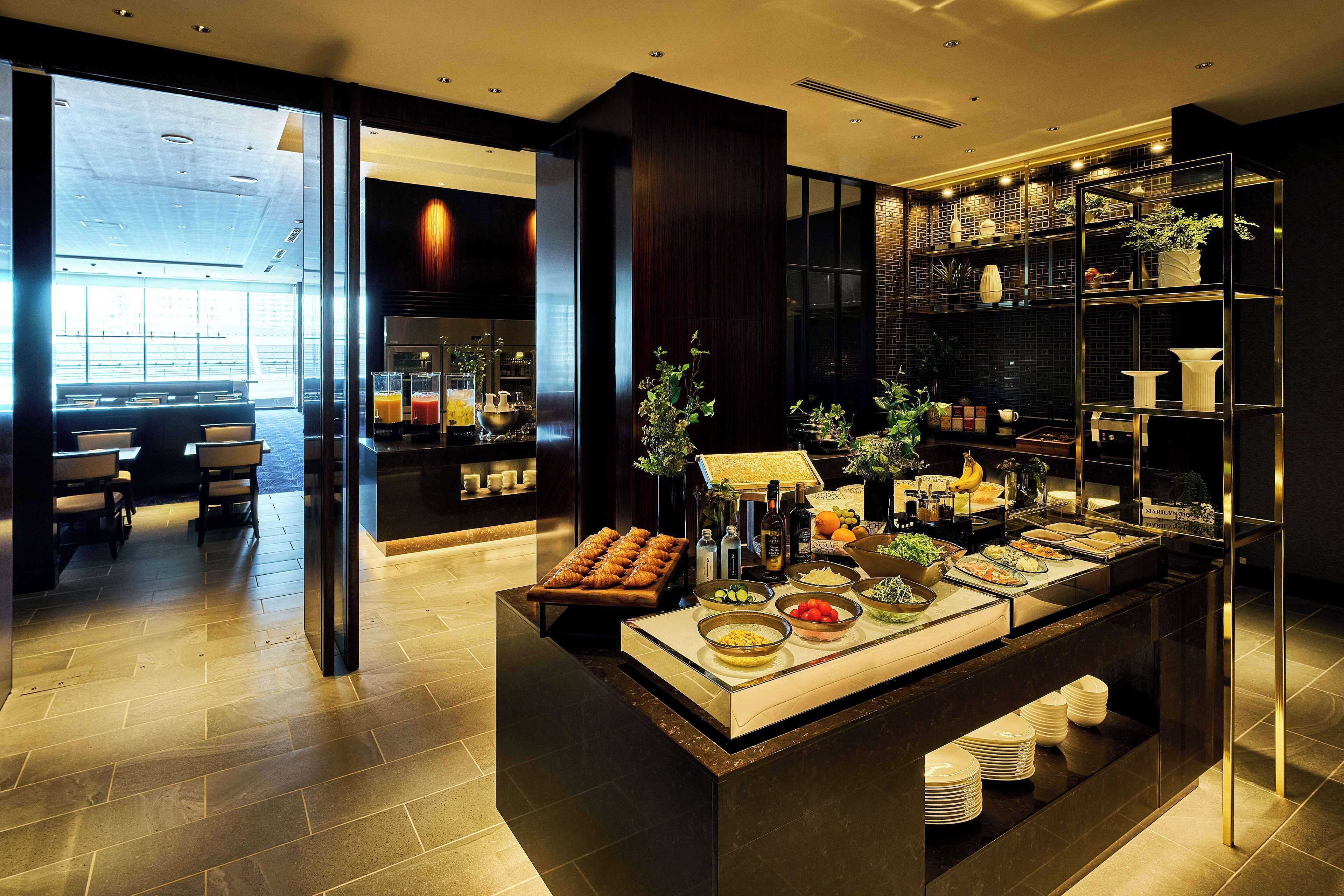 A modern breakfast bar with a variety of food options and a seating area with tables and chairs.