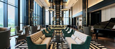 A spacious lobby with a grand piano, plush seating, and a central bar area.