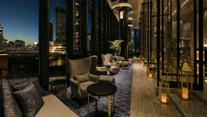 A modern lounge with sofas and tables, large windows offering city views, and decorative lanterns.