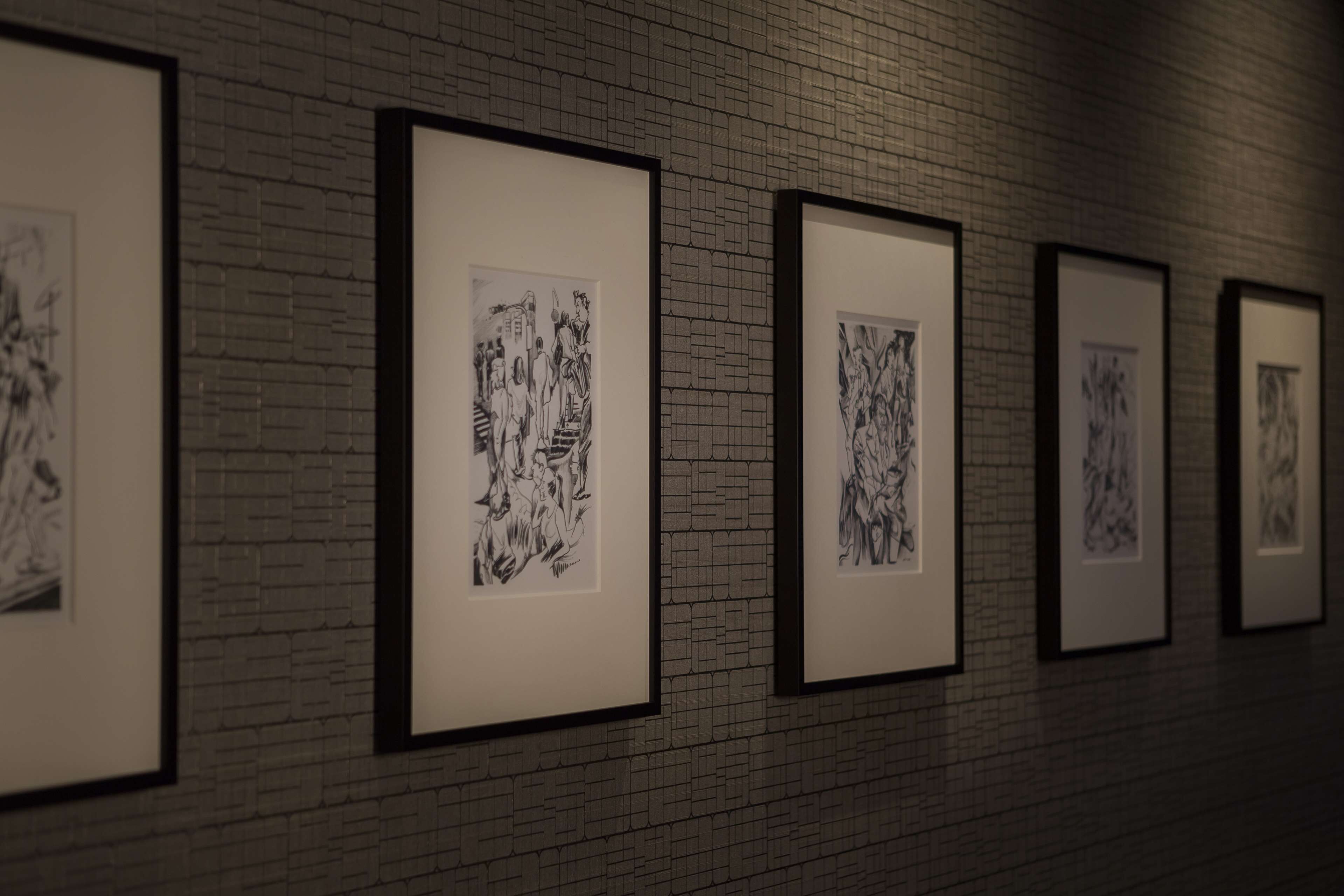 A gallery with framed black and white artworks on a brick wall.