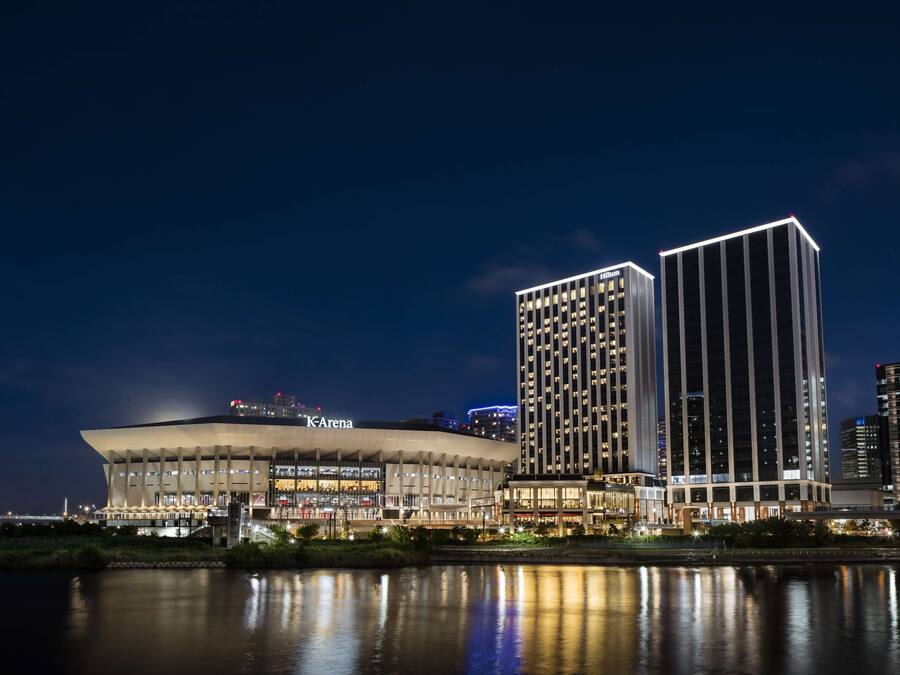 A modern building with a large, curved structure and a tall, rectangular skyscraper nearby.