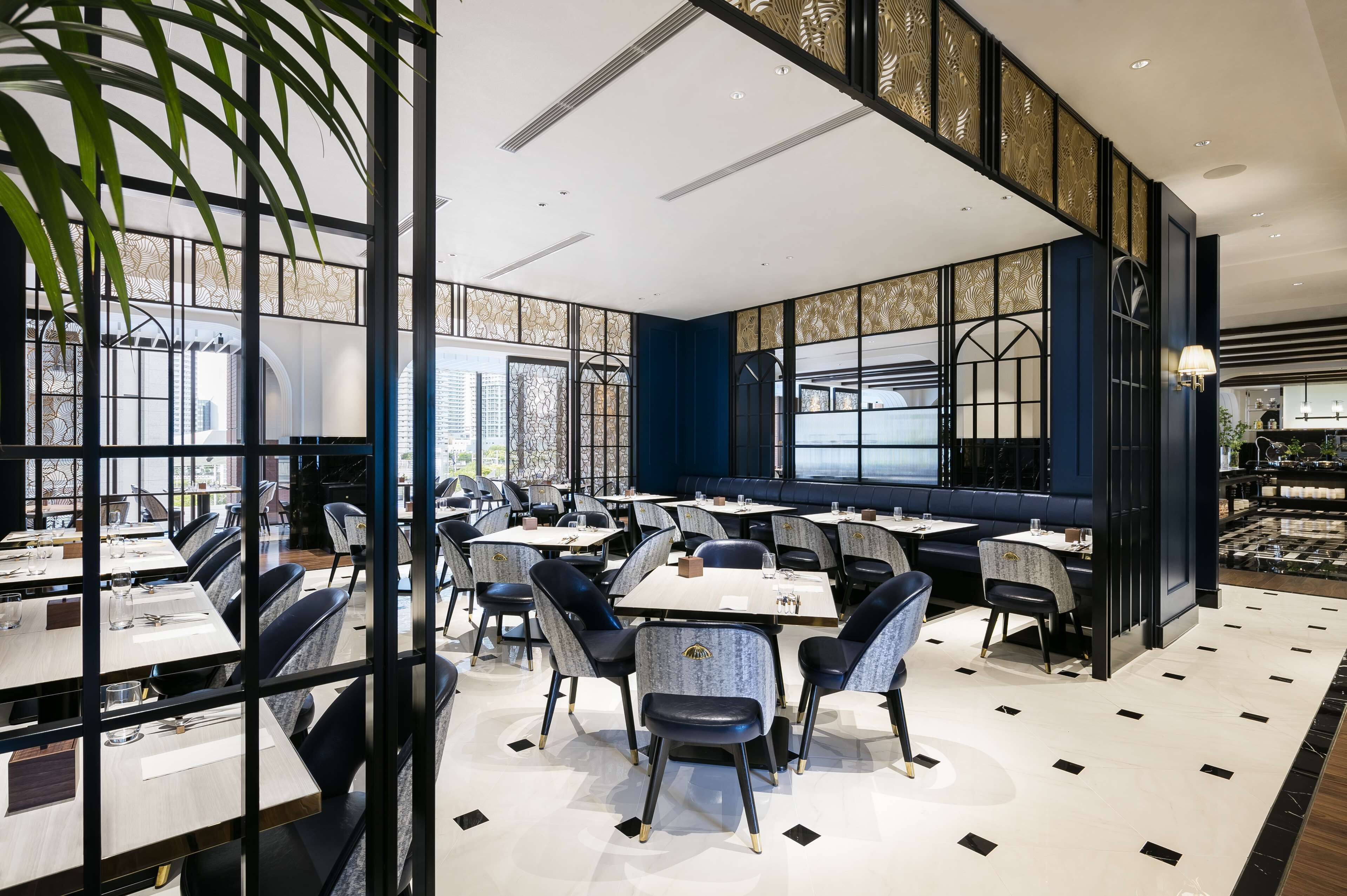 A modern dining area with tables and chairs, large windows, and decorative panels.