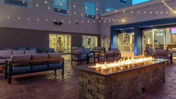 An outdoor seating area with fire feature, string lights, and modern furniture. - Hampton Inn & Suites Indianapolis West Speedway (Indianapolis)