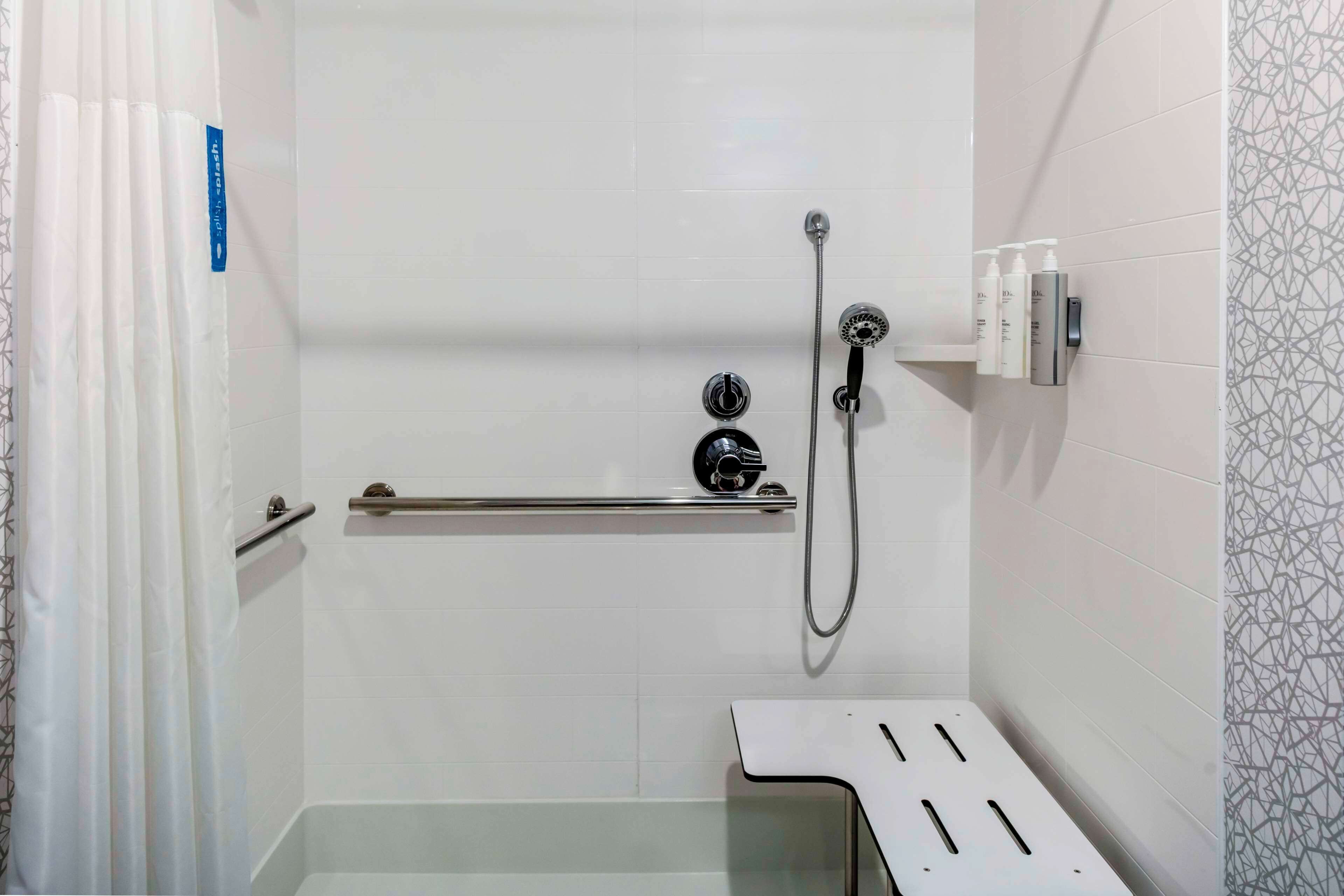 A shower with a handheld showerhead, a handheld showerhead, and a handheld showerhead.