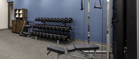 A gym with weightlifting equipment, dumbbells, and benches.