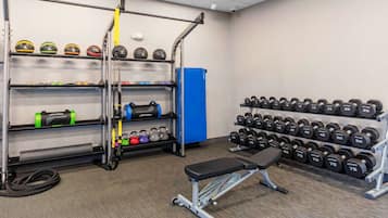 A gym with weightlifting equipment, including dumbbells and kettlebells, and a bench.