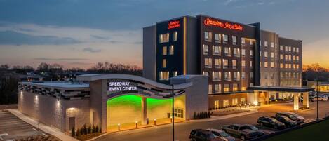 Een hotel met een bord van het Speedway Event Center, diverse parkeerplaatsen en een goed verlichte ingang.