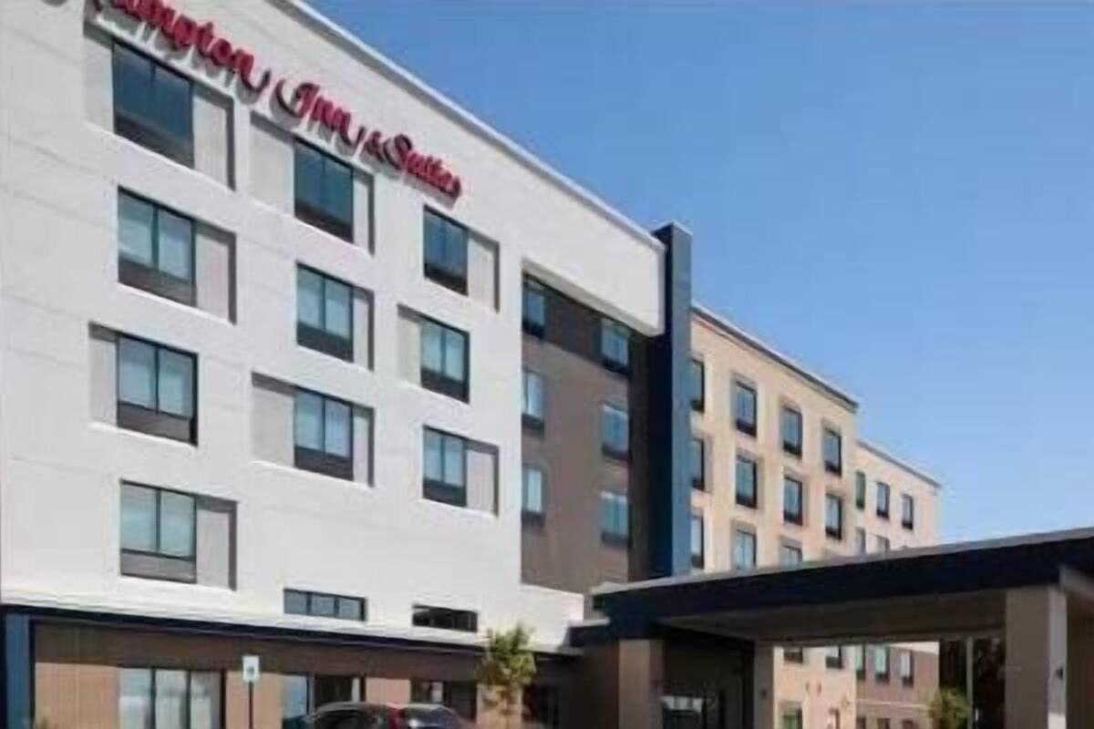 A modern hotel building with multiple floors, large windows, and a prominent sign.