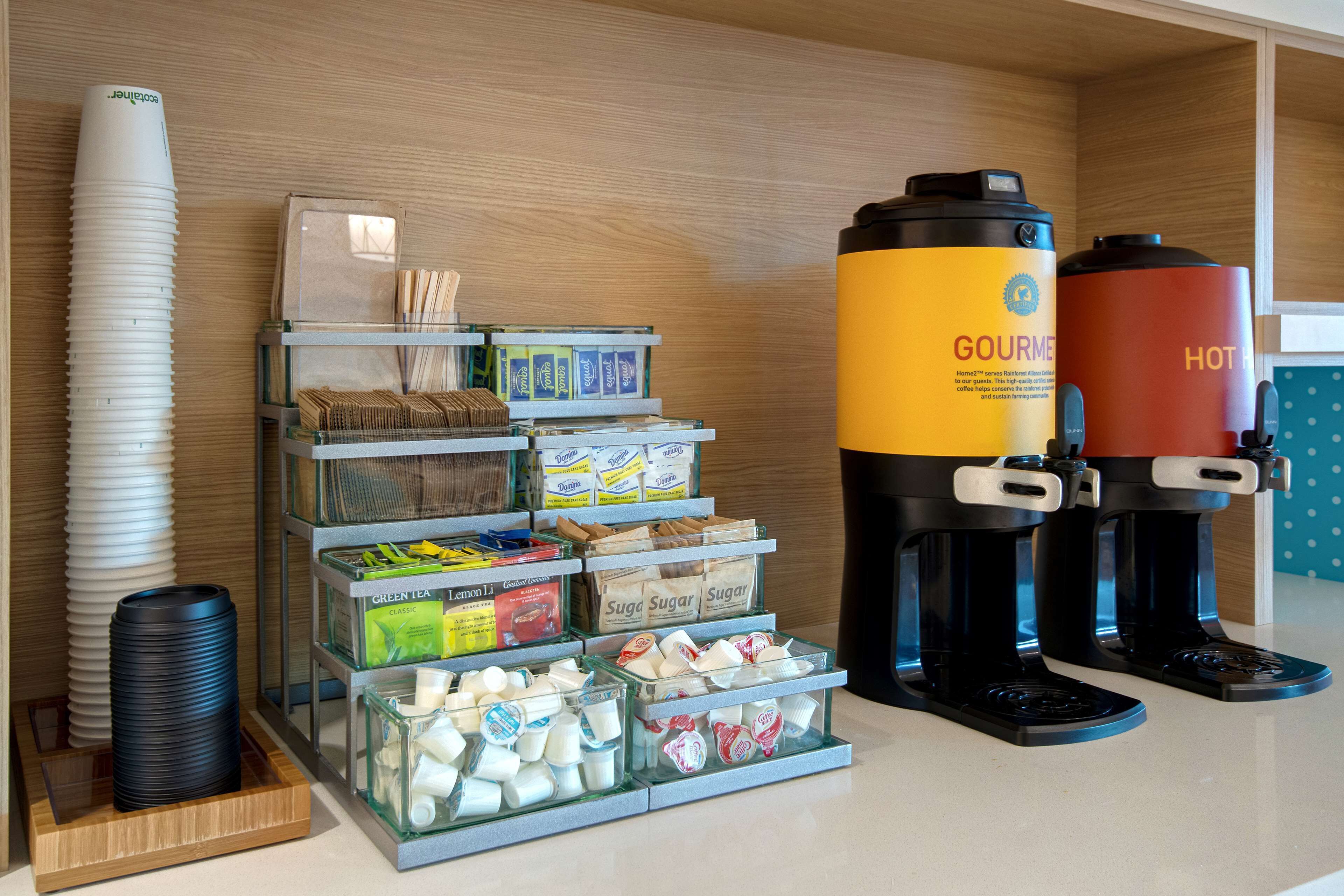 A coffee station with a coffee maker, sugar, and tea dispensers.