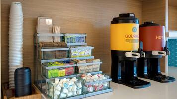 A coffee station with a coffee maker, sugar, and tea dispensers.