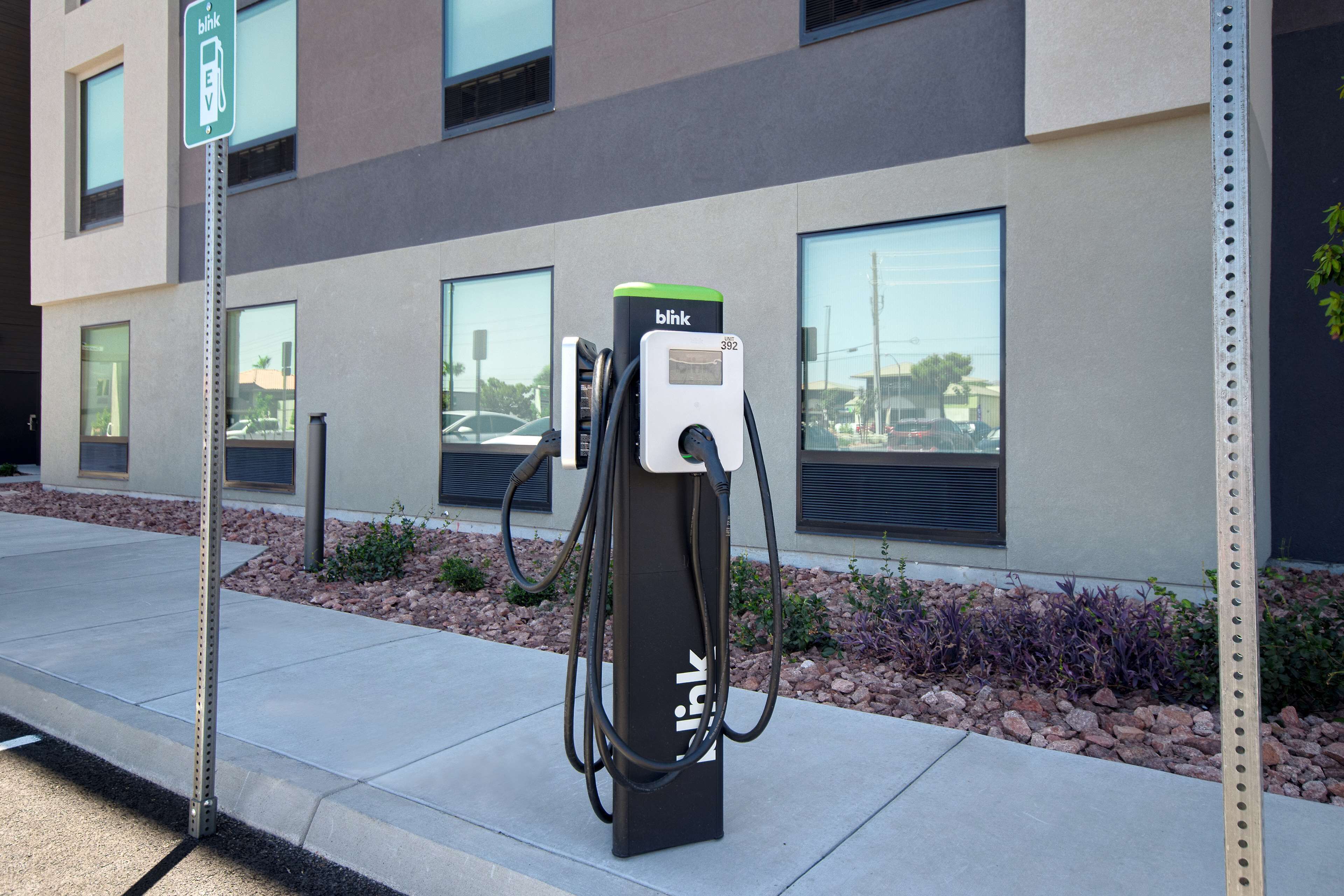 A charging station labeled 'bikb' with a number '392' on a building facade.