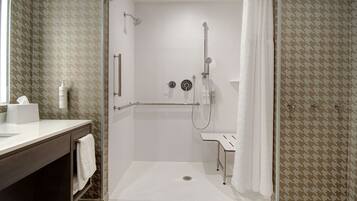 A modern bathroom with a shower, a vanity with a towel, and a patterned wall.