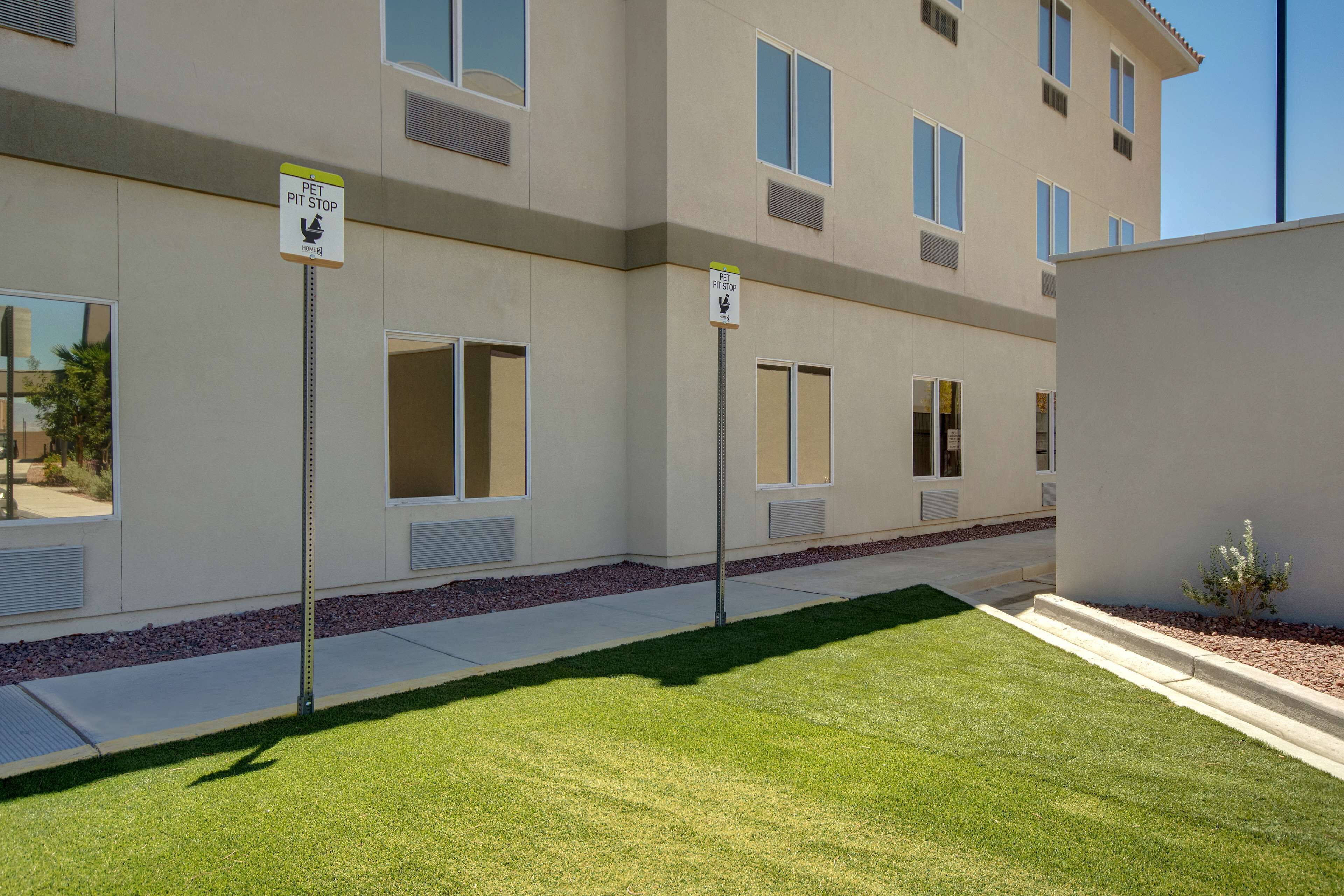 A building with pet-friendly signage, a well-maintained lawn, and a clear sky.